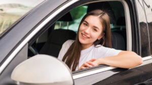 Jeune conductrice souriante dans une voiture, assurance auto adaptée pour jeunes conducteurs avec Soficca